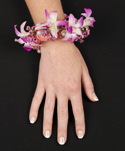 This unique floral bracelet features beautiful flowers with accents of pearls. This is definitely a creative take on a corsage.