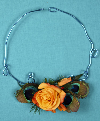 This necklace is truly fun. The feature of an orange flower with the accents of peacock feathers and blue wire makes this truly unique.